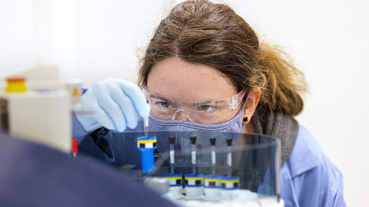female scientist looking at test tubes